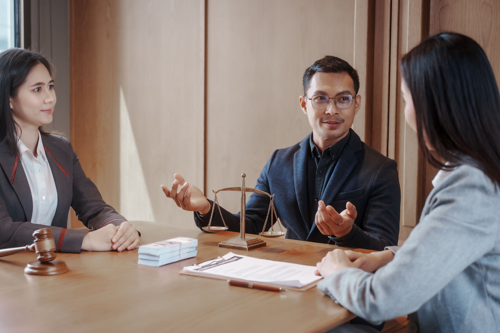 Abogado sosteniendo una balanza durante una consulta legal con clientes